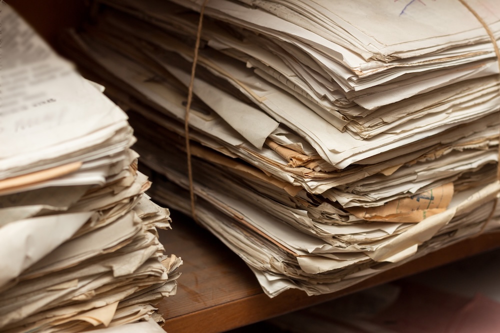 Old dusty stack of papers, files, documents on the shelves of archive room