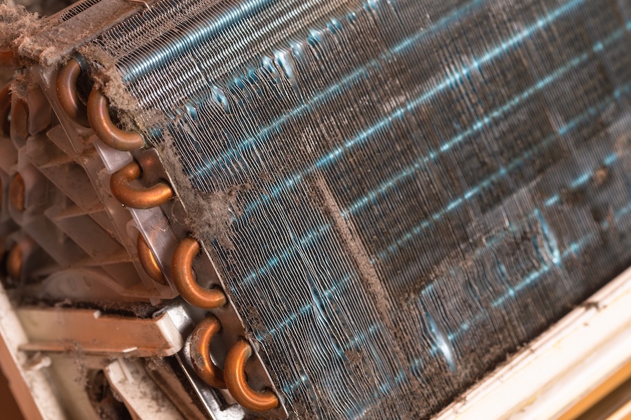 Close-up of AC condenser coils covered in dust and grime